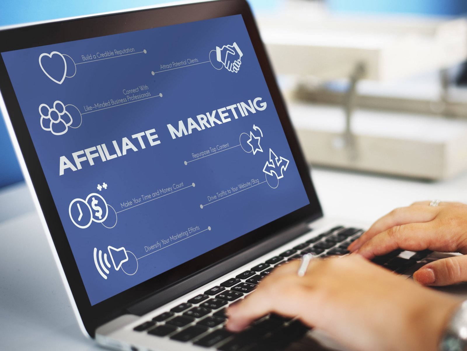 Une femme est sur son clavier et l'écran de son ordinateur affiche 'Marketing affiliate'.
